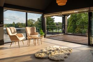 two chairs and a table in a room with large windows at Nor67 - Witley Park House in Little Witley