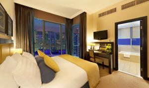 a bedroom with a large bed and a view of a city at Al Manzel Hotel Apartments in Abu Dhabi
