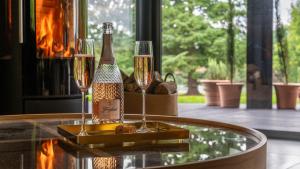 a bottle of champagne and two glasses on a table at Nor67 - Witley Park House in Little Witley
