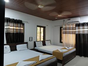 een kamer met twee bedden en een raam bij Konkan Paradise-Siddhivinayak,Devbag Beach Resort in Malvan +65 foto's