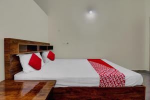 a bed with red and white pillows on it at Collection O Preethi Boarding & Lodging in Kammasandra