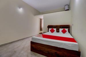 a bedroom with a large bed with red pillows at Collection O Preethi Boarding & Lodging in Kammasandra