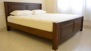 a bed with a wooden frame with two pillows on it at First House Mihintale in Mihintale