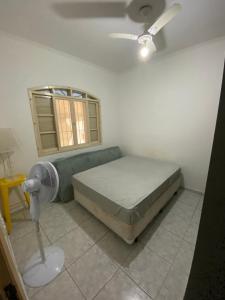 Schlafzimmer mit einem Bett, einem Ventilator und einem Fenster in der Unterkunft Casa de praia peruibe in Peruíbe
