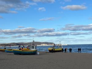 three boats on a beach with people standing around at Apartament Przytulny przy plaży in Sopot