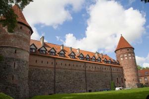 a large castle with a tower and a building at Hotel Dana in Bytów