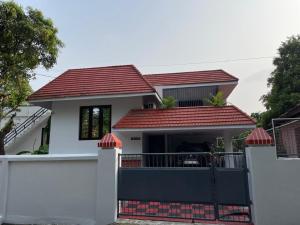 una casa con una puerta y un techo rojo en Temple Courtyard, en Chengannūr
