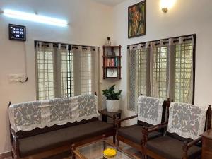 a living room with two chairs and a table at Temple Courtyard in Chengannūr