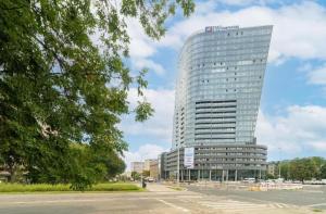 a tall building in front of a parking lot at Hanza Tower CITY 19 SPA & Pool & Jacuzzi & Sauna in Szczecin