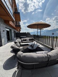 une terrasse avec des canapés, des tables et un parasol dans l'établissement KitzSki Luxury Apartment ski-in ski-out accommodation, à Mittersill