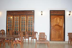 a dining room with a table and chairs and a wooden door at First House Mihintale in Mihintale