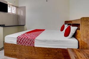 a bedroom with a bed with red and white pillows at Collection O Preethi Boarding & Lodging in Kammasandra