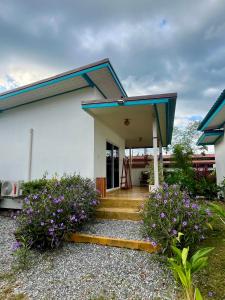 a white house with a blue roof and some flowers at The Summer Cottage in Khlaung Phai Bae
