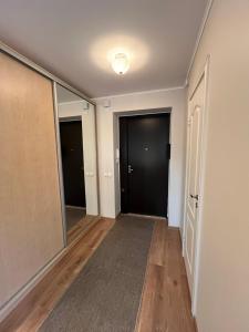 an empty hallway with black doors and wood floors at Уютная квартира в 10 минутах от моря in Aseri