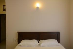 a bed with two pillows and a light on the wall at First House Mihintale in Mihintale