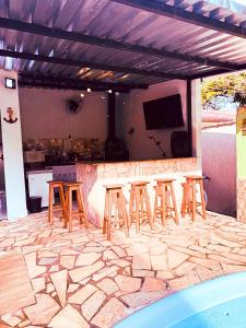 a patio with a bar with stools and a tv at Ares da Bocaina Suítes in Bananal