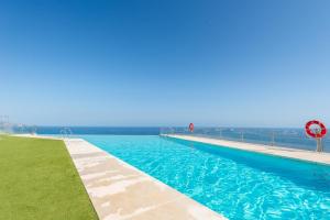 a large swimming pool with blue water and acean at Breathtaking Bay views Nerja in Torrox