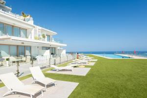 a row of lounge chairs on a lawn next to a building at Breathtaking Bay views Nerja in Torrox