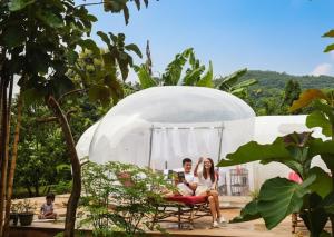 a man and a woman sitting on a bench in a dome at Safari Bubbles in Wundanyi