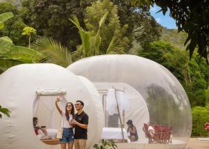 a man and a woman standing in front of a circular house at Safari Bubbles in Wundanyi