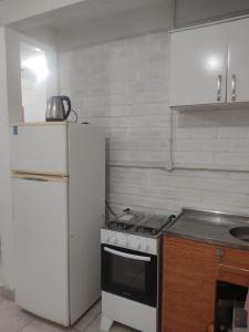 a kitchen with a white refrigerator and a stove at Casa Térrea de praia confortável para famílias in Tramandaí