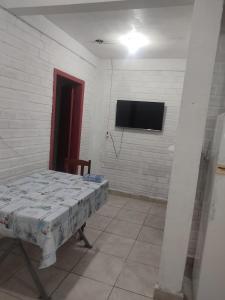 a room with a table and a tv on a wall at Casa Térrea de praia confortável para famílias in Tramandaí +4 photos