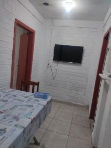 a room with two beds and a tv on a wall at Casa Térrea de praia confortável para famílias in Tramandaí