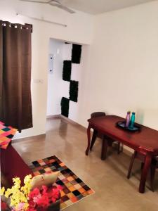 ein Wohnzimmer mit einem Holztisch und einer Wand in der Unterkunft Olive Villa ECR - Private 2 BHK villa in Tirupporūr