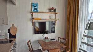 a dining room with a table and a tv on the wall at Minihuset nära havet in Varberg
