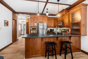 eine Küche mit Holzschränken und schwarzen Barhockern in der Unterkunft Les Manoirs Wpool & Hot Tub Near Village 120-7 in Mont-Tremblant