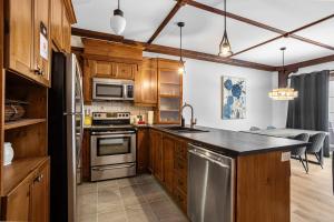eine Küche mit Küchengeräten aus Edelstahl und Holzschränken in der Unterkunft Les Manoirs Wpool & Hot Tub Near Village 120-7 in Mont-Tremblant