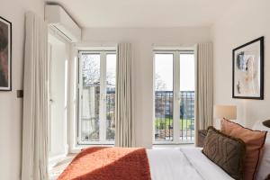 a white bedroom with large windows and a bed at 2-Bed Apartments a Short Walk to Wembley Stadium in London