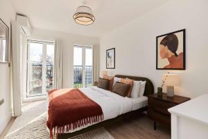 a white bedroom with a large bed and windows at 2-Bed Apartments a Short Walk to Wembley Stadium in London