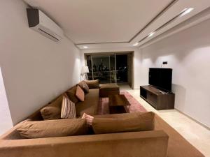 a living room with a couch and a flat screen tv at Luxury Prestigia Fes - 7 Appartements - Vue Parc ou Quartier in Fès