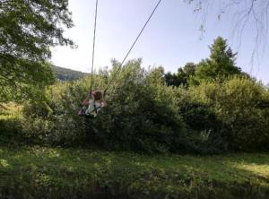 une petite fille se balançant sur une balançoire en corde dans l'établissement Lička Vodenica Rustical Oasis, à Modruš