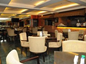 un restaurante con mesas y sillas blancas y un bar en CityState Tower Hotel en Manila