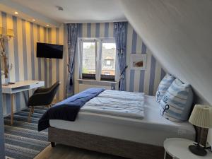 a bedroom with a bed and a desk and a window at Pension Zur Brandung in Büsum