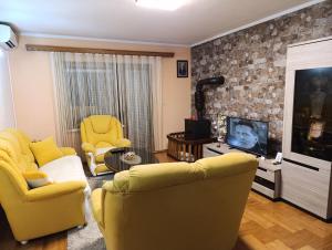 a living room with two yellow chairs and a television at Stan na dan Ilicka in Brčko