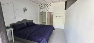 ein Schlafzimmer mit einem lila Bett in einem weißen Zimmer in der Unterkunft Khao Ban Eing in Ban Khlong Sai