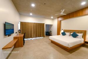 une chambre avec un grand lit et une télévision dans l'établissement Leisure Resort, à Pondichéry