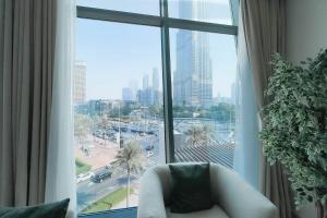 a room with a large window with a white chair in front at Luxurious 3 BR with Burj Khalifa View in Downtown in Dubai