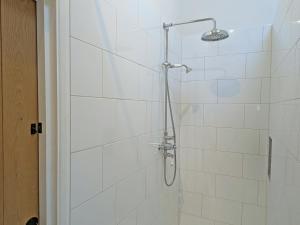 a shower in a bathroom with white tiles at The Stables - Uk50804 in Cratfield