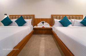two beds with a stuffed animal sitting between them at Leisure Resort in Pondicherry
