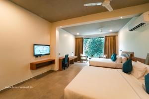a hotel room with two beds and a flat screen tv at Leisure Resort in Pondicherry