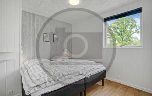 Un dormitorio con una cama con una ventana grande. en 6 Bedroom Awesome Home In Glesborg, en Fjellerup Strand