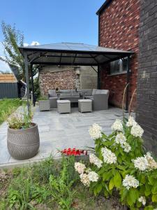 eine Terrasse mit Sofas, Tischen und Blumen in der Unterkunft Dukes View -explore Haspengouw & surrounding towns in Zoutleeuw