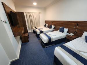 a hotel room with three beds and a flat screen tv at فندق اصول الجوهرة بالعزيزية توصيل مجاني الى الحرم Asoul Al Jawhara Al Azizia Free Shuttle Service in Al ‘Azīzīyah