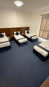 three beds in a room with blue carpet at فندق اصول الجوهرة بالعزيزية توصيل مجاني الى الحرم Asoul Al Jawhara Al Azizia Free Shuttle Service in Al ‘Azīzīyah +30 photos