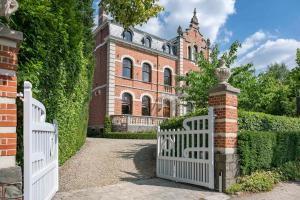 a white gate in front of a brick building at Villa Copis in Borgloon