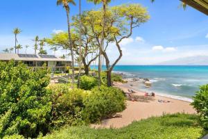 a beach with palm trees and people in the water at Napili Bay 210 · NB 210 Napili Bay Studio with Direct Ocean View in Kahana